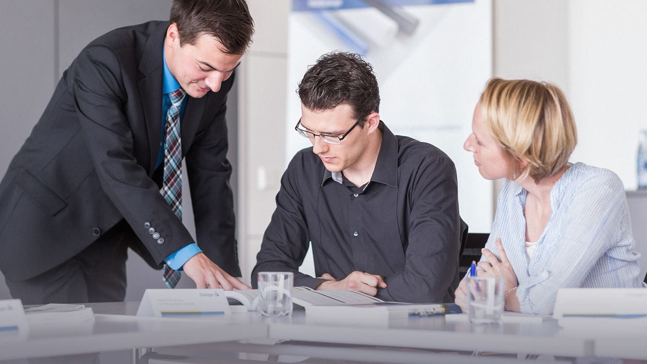 Training scene: Two people listening as Ensinger employee explains an issue